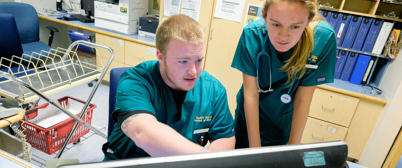 Two Nursing Students in scrubs looking at monitor
