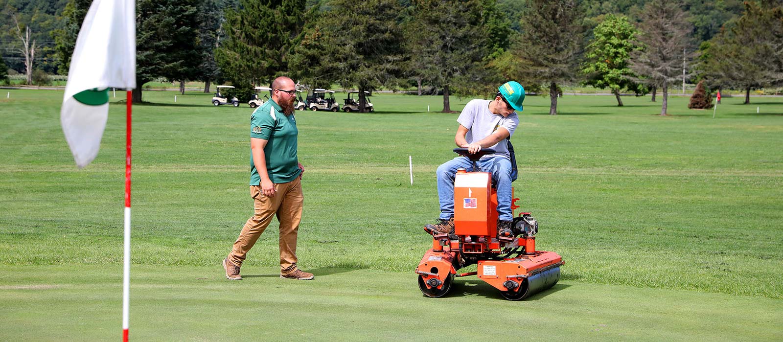 Professor teaching a student how to groom a golf green