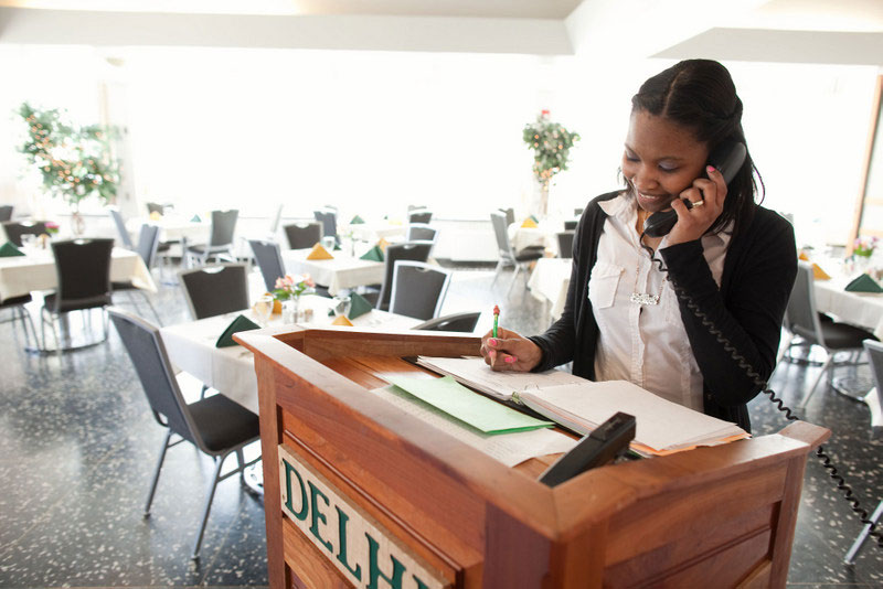 Student taking reservations by phone for student restaurant
