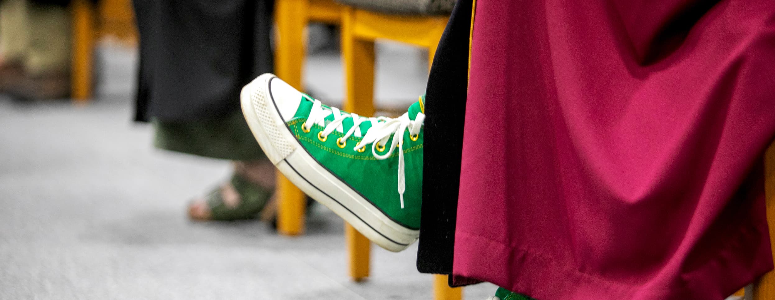 A pair of green sneakers with bottom of maroon robe